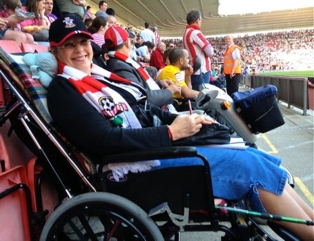 Image of Elizabeth in a football crowd, pitch-side; at a Southampton Saints game taking a break from writing